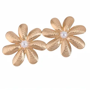 Eleganti orecchini a lobo a fiore dorati con petali testurizzati e perla centrale.