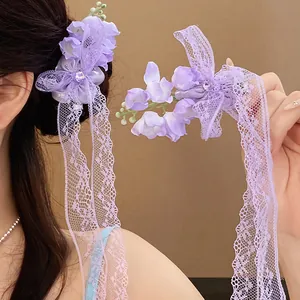 Détail d'une pince à cheveux muguet violette avec strass et longs pompons en dentelle.