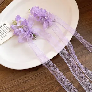 Détail de pinces à cheveux violettes en forme de muguet avec de longs pompons en dentelle