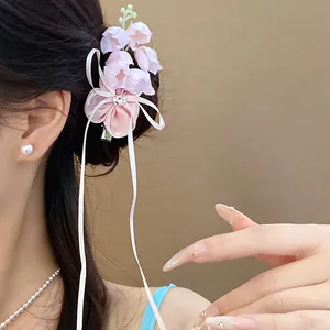 Gros plan d'une pince à cheveux muguet rose avec des rubans portée par un mannequin