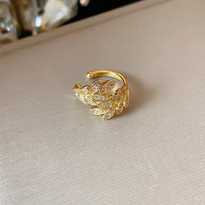 Dettaglio dell'orecchino a polsino dorato a forma di spiga con zirconi scintillanti.