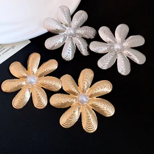 Dettaglio di orecchini vintage a fiore con centro in perla e petali testurizzati.