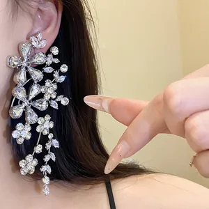 Primer plano de elegantes pendientes colgantes de flores plateadas con brillantes diamantes