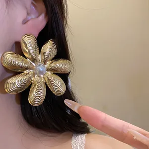 Dettaglio di un grande orecchino a fiore dorato con perla in stile retrò chic