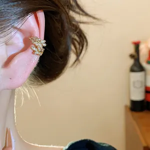 Vista dettagliata di un ear cuff a spiga di grano dorato con zirconi brillanti