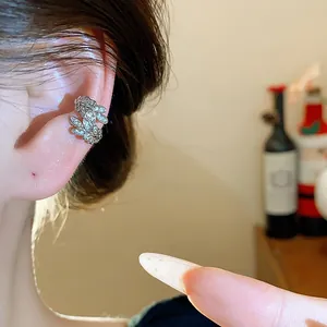 Vista dettagliata di un ear cuff a spiga di grano con zirconi indossato sull'orecchio.