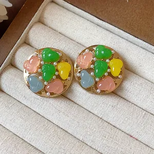 Close-up view of colorful resin gourd and pearl round stud earrings in a jewelry box