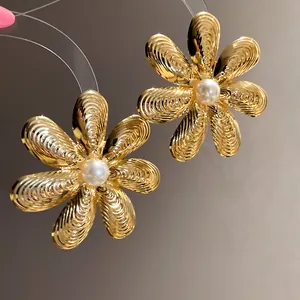 Primo piano di orecchini a fiore dorati vintage con petali texturizzati e perla
