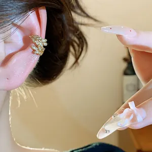 Primo piano dettagliato di un ear cuff a spiga di grano con zirconi dorati lucidi