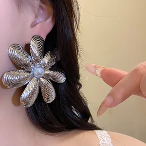Dettagliato primo piano di un grande orecchino a fiore d'argento con perla bianca centrale