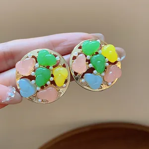 Close-up of elegant colorful resin and pearl round stud earrings with gold finish