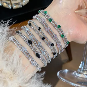 Detail showing layered 18k gold plated zircon bracelets with multi-colored stones on a wrist