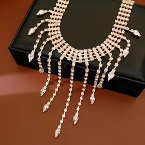 Macro detail of luxury gold waterdrop tassel necklace with sparkling rhinestones on box.
