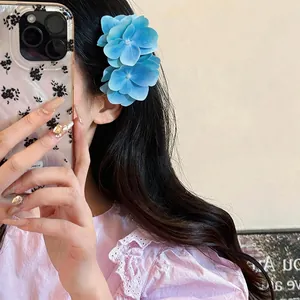 Nahaufnahme der exquisiten blauen Hortensien-Haarspange aus Stoff am Haar des Modells