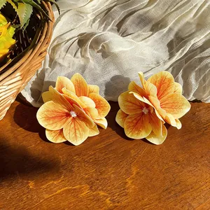 Detailansicht von zwei eleganten orangefarbenen Stoffblumen-Haarspangen auf Holz