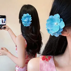 Nahaufnahme einer eleganten blauen Stoffblumen-Haarspange mit Perle in langem schwarzen Haar