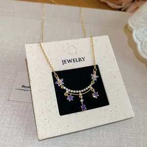 Detailed view of 18k gold plated necklace with purple zircon flower and teardrop pendants