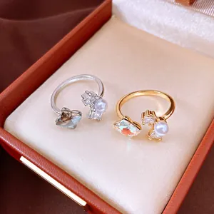 Close-up of elegant zircon and pearl flower open rings in gold and silver within a gift box
