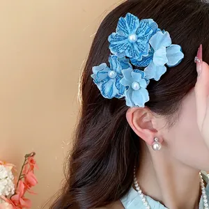 Elegant blue fabric flower hair clip with pearls worn by model for beach vacation style