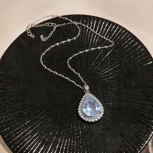 Close-up of elegant pear-shaped blue zircon pendant with silver-toned textured chain.