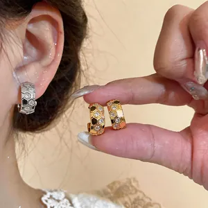 Detailed view of gold and silver honeycomb C-shaped hoop earrings set with zircon stones
