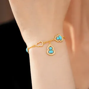 Macro view of 18K gold plated hulu charm bracelet with turquoise stones and zircons