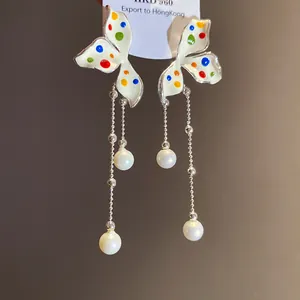 Dettaglio degli orecchini a farfalla con pois colorati, nappe argentate e perle