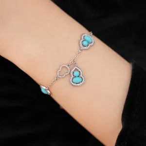 Close-up detail of silver gourd bracelet with turquoise stones and heart charms on wrist