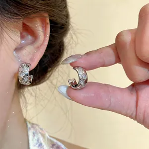 Detail view of silver C-shaped zircon earrings with a honeycomb textured design