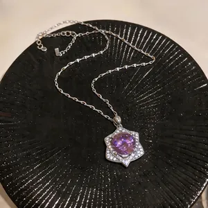 Close-up of a purple zircon pendant necklace with a vintage palace design on a black plate.