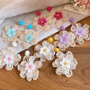 Detailed view of handmade raffia flower drop earrings in various pastel colors