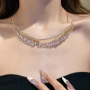 Primo piano di un choker dorato con zirconi luccicanti a goccia indossato sul collo