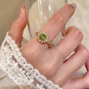 Elegante anello a fiore in oro vintage con gemma verde e accenti di zircone sulla mano