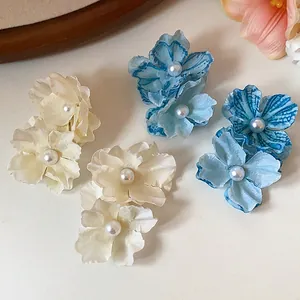 Close-up of elegant fabric flower hair clips with central pearls in blue and cream