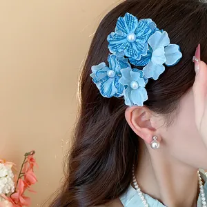 Detailed side view of blue fabric flower hair clips with pearls on a model's hair