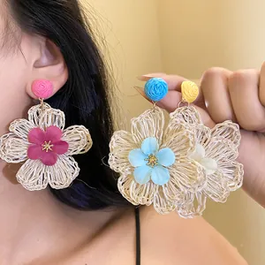 Close-up of vibrant Raffia flower earrings with intricate woven petals and colorful center details