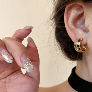 Close-up detail of 18k gold plated C-shape earrings with black honeycomb pattern