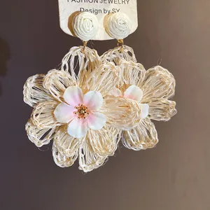 Close-up of handmade raffia flower earrings with delicate fabric blossom centers