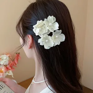 Detailed macro view of cream fabric flower hair clips on long dark hair for styling