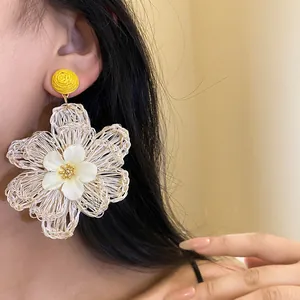 Close-up detail of large woven raffia flower earrings for vacation style
