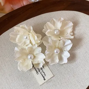 Close-up of elegant cream fabric flower hair clips with pearl centers for beach vacation