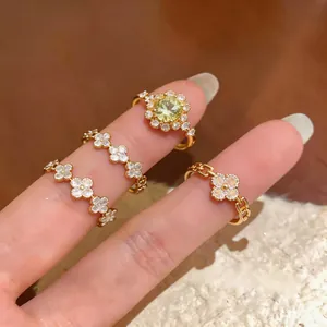 Dettaglio di eleganti anelli a fiore in zircone dorato indossati su sfondo morbido
