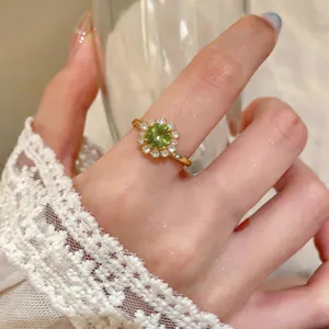 Primo piano di un elegante anello a forma di fiore con zircone verde indossato al dito