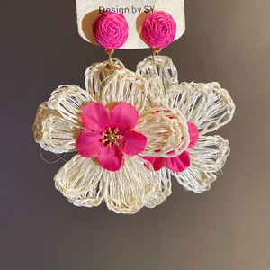 Close-up view of pink and white raffia woven flower drop earrings for summer vacation.
