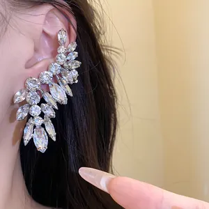 Close-up view of silver needle earrings with leaf-shaped marquise crystals worn on the ear.