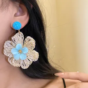 Close-up view of a sweet hand-woven cream raffia flower earring worn by a model