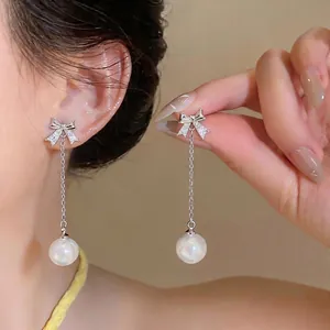 Elegant silver bowknot stud earrings with zircon inlay and dangling pearl tassel