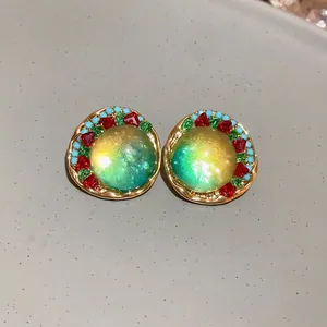 Macro detail view of forest-style round geometric stud earrings with colorful stone accents