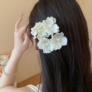 Close-up of elegant white fabric flower hair clips with pearls styled on dark hair