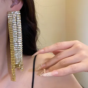 Detailed close-up showing elegant asymmetric gold mesh tassel earrings on a model